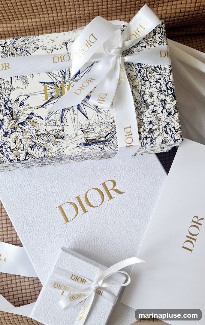 Several Dior branded gift boxes and shopping bags are arranged together. One box is wrapped with a white ribbon featuring the Dior logo. The wrapping paper has a toile de Jouy pattern with ships and floral motifs. Another larger white box prominently displays the embossed Dior logo. A white shopping bag with the Dior logo is also visible.