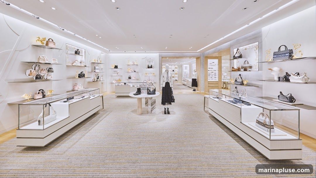 A well-lit, modern luxury store interior, likely a boutique, showcasing a collection of designer handbags and accessories. The store features white walls, sleek display shelves, and glass display cases. Mannequins are dressed in elegant attire, and decorative golden animal figurines are placed on shelves. The overall aesthetic is clean, minimalist, and high-end.