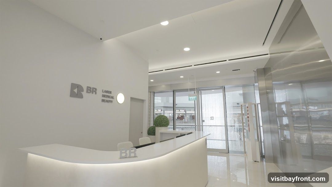 A modern and clean reception area with a white counter and chairs. The logo 'BR LASER MEDICAL BEAUTY' is visible on the wall. Large glass doors lead to the outside, with an 'EXIT' sign visible.