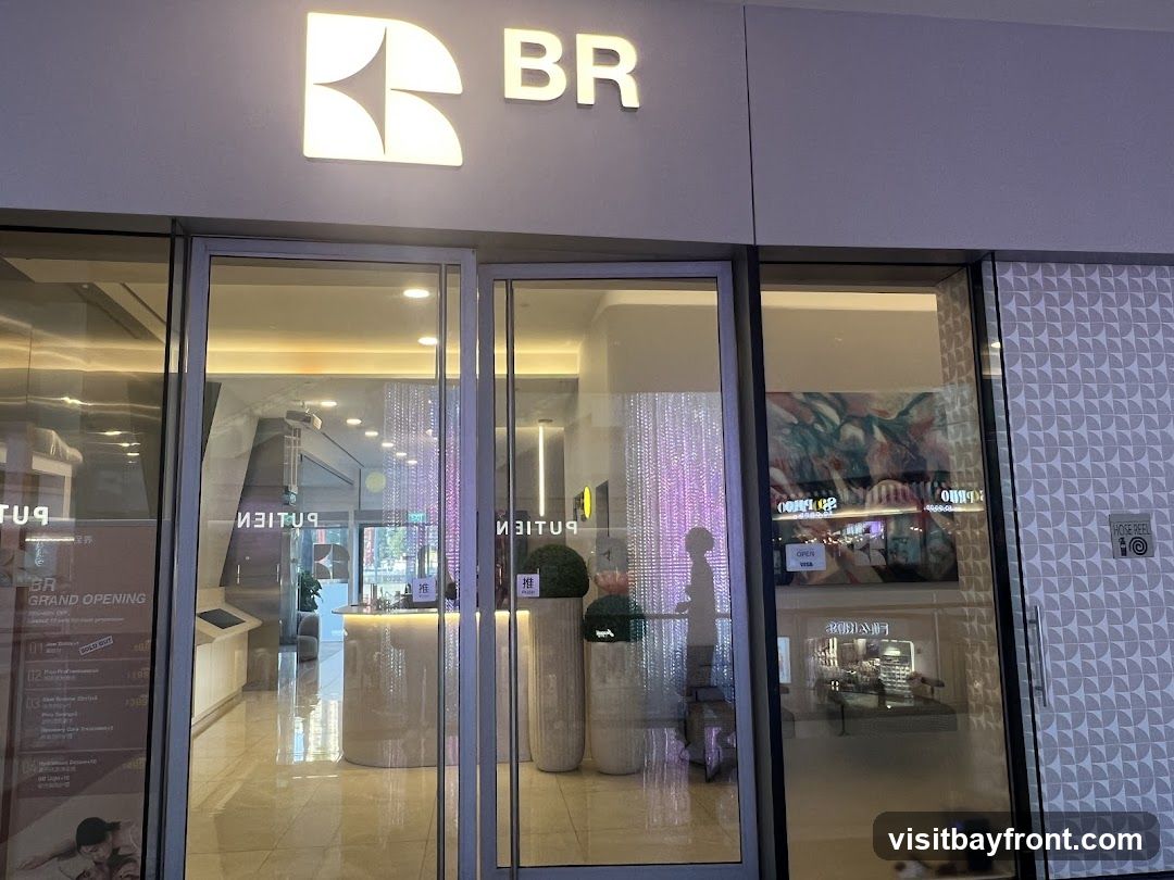 The exterior of a BR restaurant with large glass doors and windows. The BR logo and name are visible above the entrance. Inside, a counter and decorative lighting can be seen. A promotional poster for the grand opening is displayed on the left, listing services and prices.