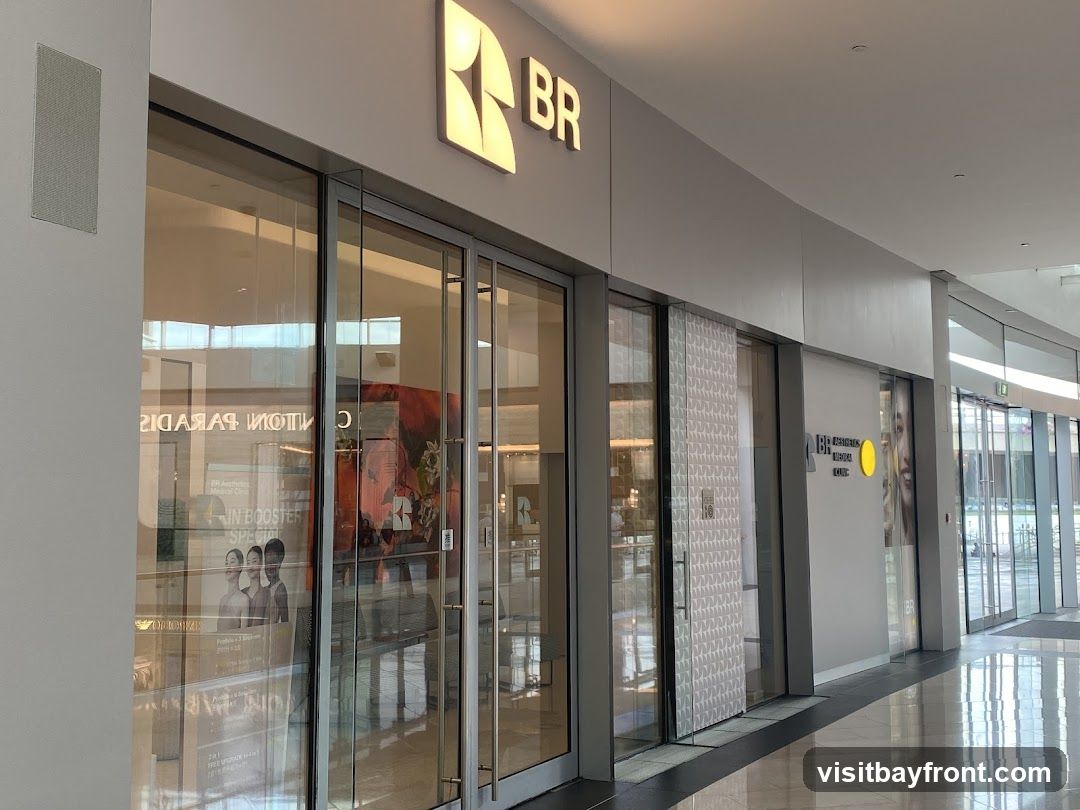 The exterior of a BR Aesthetics Medical Clinic with large glass doors and windows. A prominent illuminated BR logo is visible above the entrance. Inside, reflections show posters and displays.