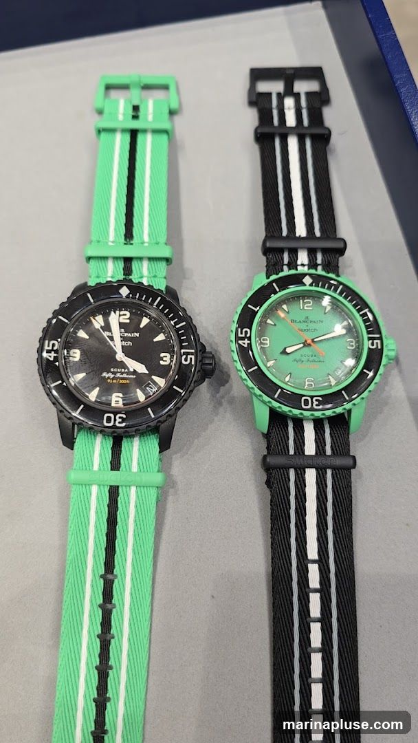 Two watches are displayed side-by-side. The watch on the left has a black dial and bezel with a green, white, and black striped strap. The watch on the right has a green dial and bezel with a black, white, and green striped strap. Both watches have the Swatch logo visible on the strap.