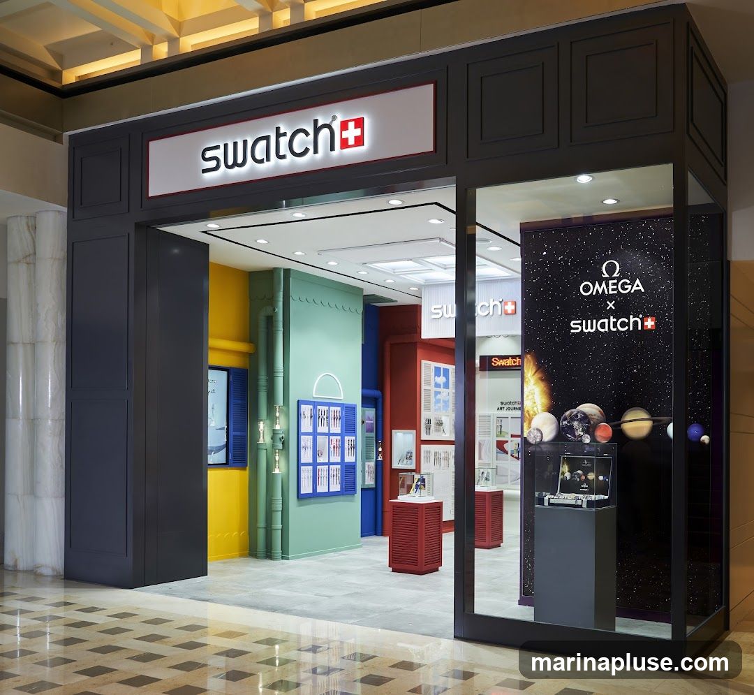 The exterior of a Swatch store with a prominent "swatch+" logo above the entrance. The store features a colorful interior with displays of watches. A large graphic on the right side of the storefront shows "OMEGA x swatch+" with celestial imagery.