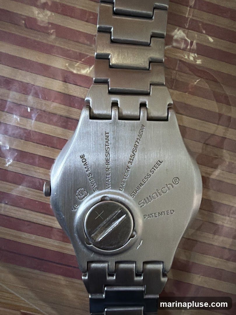 The back of a Swatch watch is shown, with text indicating it is Swiss made, water-resistant, uses a battery 315/SR716SW, is stainless steel, and patented. The Swatch logo is visible.
