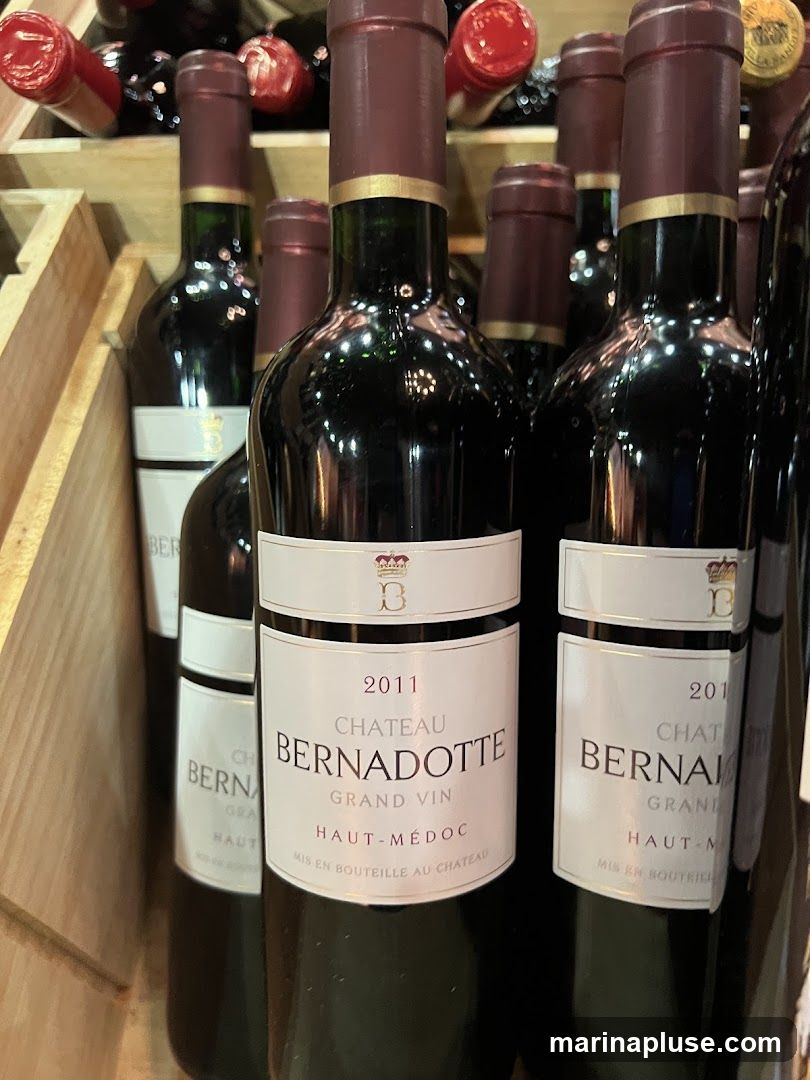 Several bottles of red wine are displayed in wooden crates. The labels on the bottles indicate they are from "Chateau Bernadotte" and are "Grand Vin Haut-Médoc" from the year 2011.