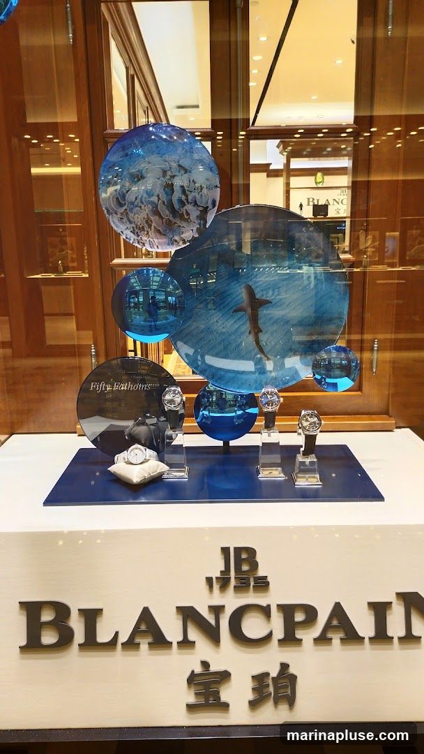 A display window showcasing Blancpain watches. The window features circular decorative elements with images of marine life, including jellyfish and a shark. Several Blancpain watches are displayed on stands. The Blancpain logo and Chinese characters are visible on a panel below the watches.