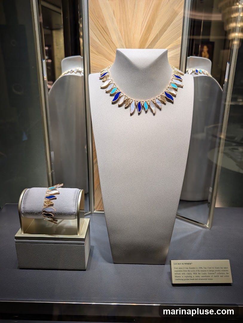 A display case features a necklace and bracelet with blue, white, and turquoise accents, set against a backdrop of light wood and mirrors. A small plaque describes the 'Lucky Summer' collection by Van Cleef & Arpels.