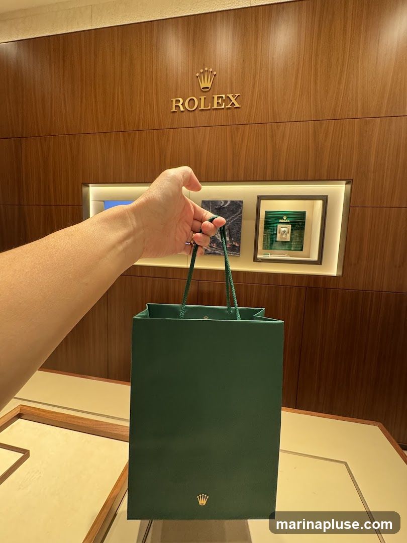 A hand holds a green Rolex shopping bag in front of a Rolex display wall. The Rolex logo is visible on the wall and on the bag.