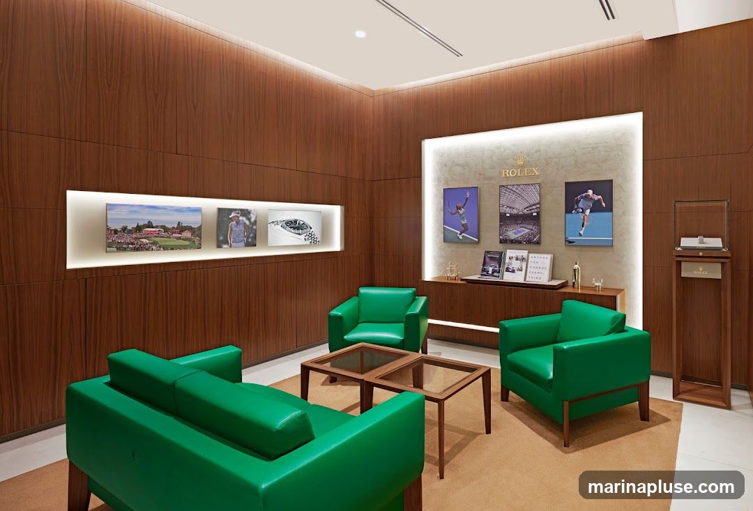 A luxurious Rolex showroom with wood-paneled walls, featuring green leather seating arrangements around glass-topped coffee tables. The walls display framed images of golf tournaments, tennis players, and Rolex watches. A prominent Rolex logo is visible above a display shelf with books and promotional materials. A glass display case with a watch is positioned on a wooden stand to the right.