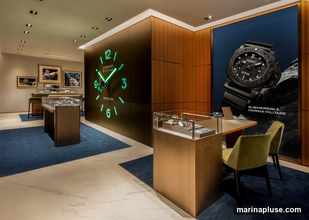 The interior of a modern watch store, featuring a large neon clock on the wall with the Panerai logo. Display cases showcase watches, and a large advertisement for a Panerai Submersible watch is visible. The store has a luxurious feel with wooden accents, marble flooring, and blue carpets.