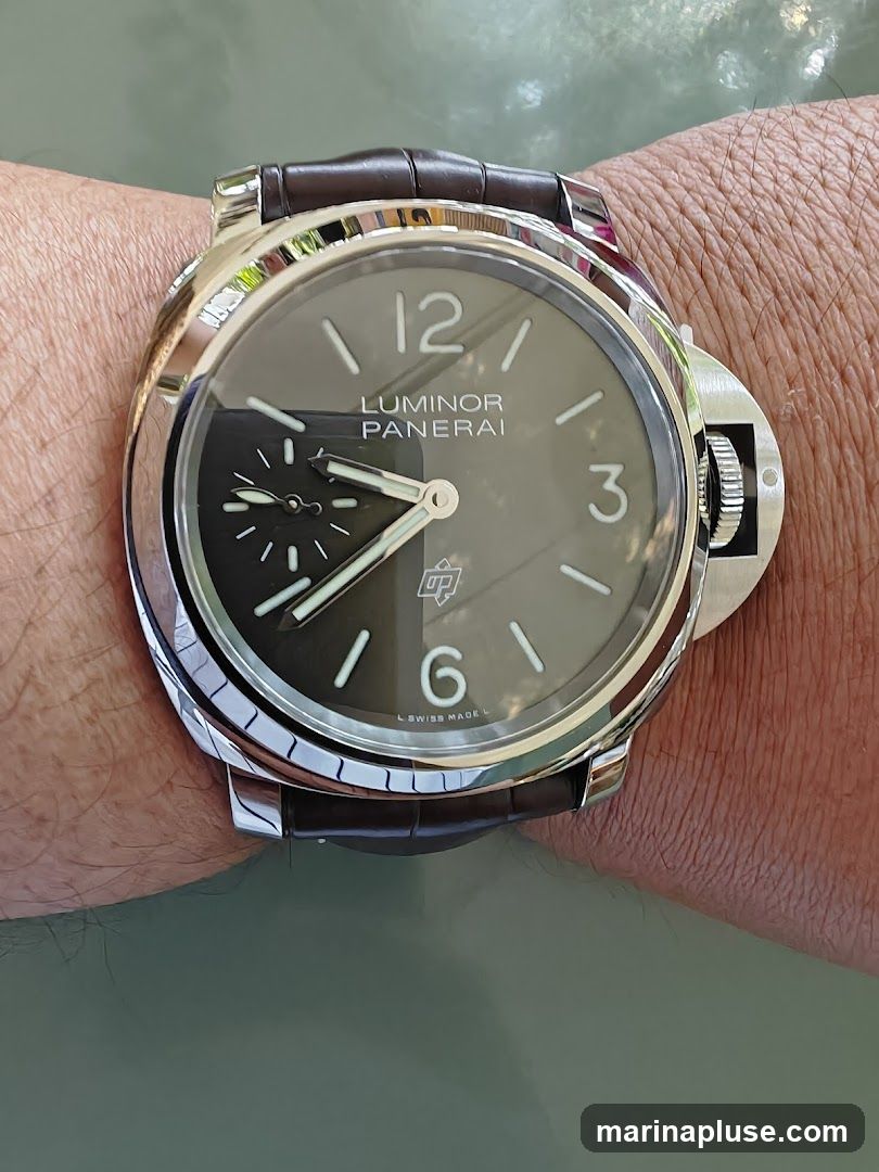 A close-up shot of a Panerai Luminor watch on a person's wrist. The watch has a dark dial with luminous hour markers and hands. The brand name "LUMINOR PANERAI" is visible on the dial, along with "SWISS MADE" at the bottom. The watch features a brown leather strap and a distinctive crown guard.