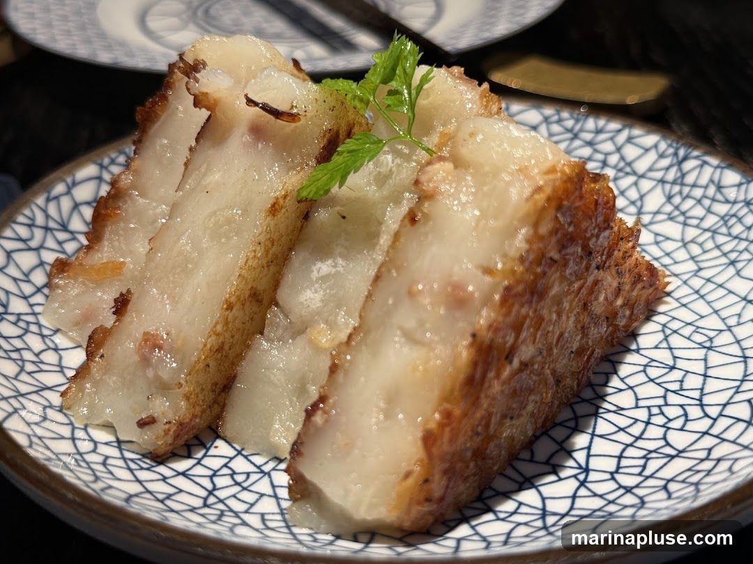 Three slices of fried turnip cake are served on a blue and white patterned plate. The cake has a crispy golden-brown exterior and a soft, white interior with visible pieces of turnip and possibly meat. A sprig of green herb garnishes the top slice.