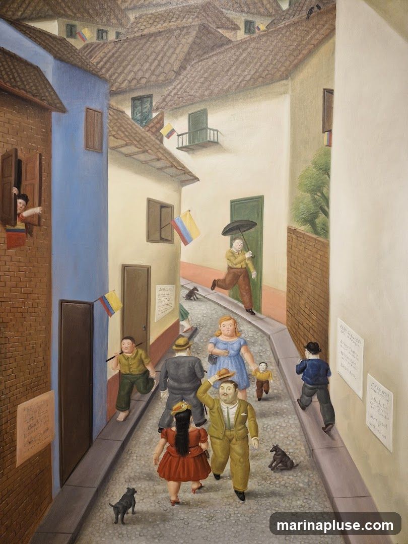 A painting depicts a narrow cobblestone street lined with buildings. Several people, including men, women, and children, are walking in the street. Some buildings have windows with people looking out, and Colombian flags are displayed. There are also dogs in the street. Some posters are affixed to the walls.