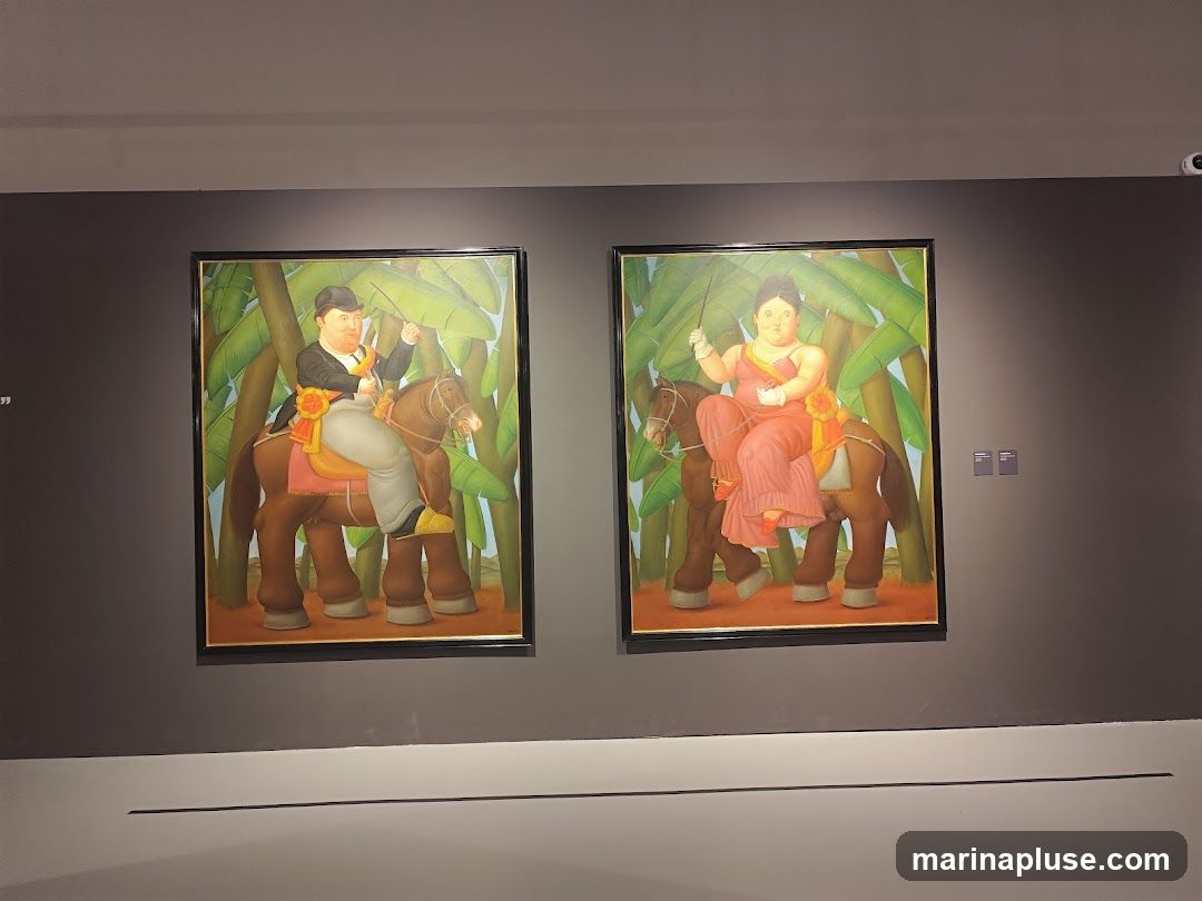 Two framed paintings are displayed on a dark gray wall. The painting on the left depicts a man in a suit and hat riding a brown horse, holding a banana. The painting on the right shows a woman in a pink dress riding a brown horse, also holding a banana. Both figures and horses are depicted in a rounded, stylized manner, characteristic of Fernando Botero's art. Large green leaves form the background in both paintings.