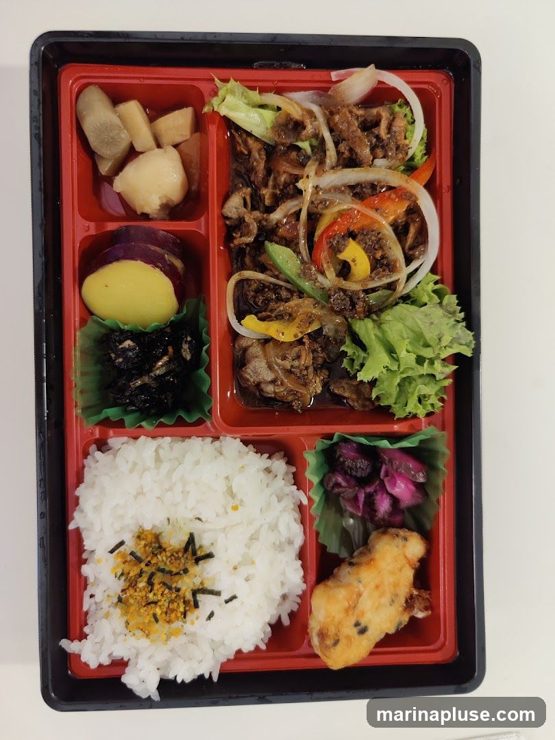 A bento box with various food items including rice, stir-fried meat with vegetables, sweet potato, pickled vegetables, and a fried item.