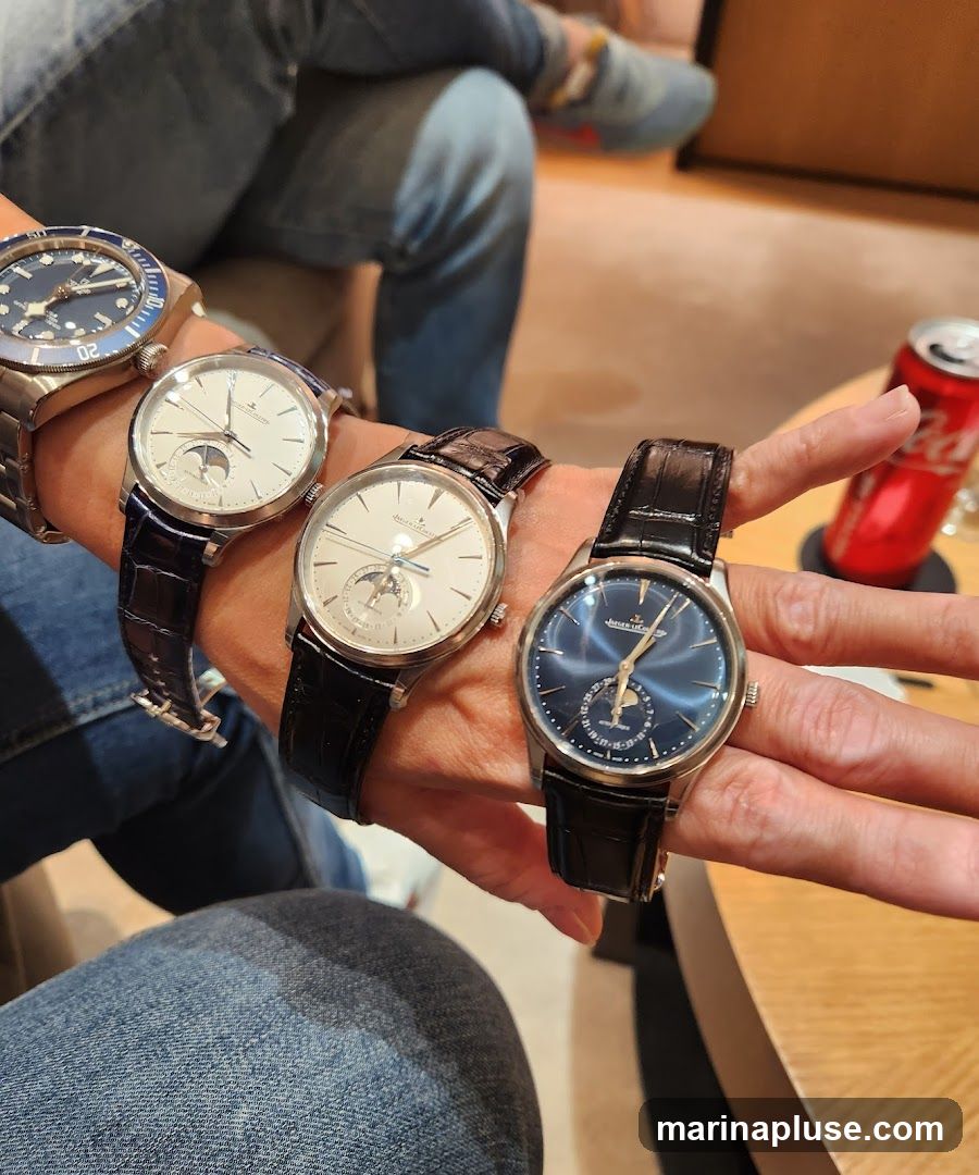 Four watches are displayed on people's wrists. One watch has a blue face and a metal band. The other three watches have white or blue faces and black leather bands. One of the watches with a white face has a moon phase complication. A red can is visible in the background.