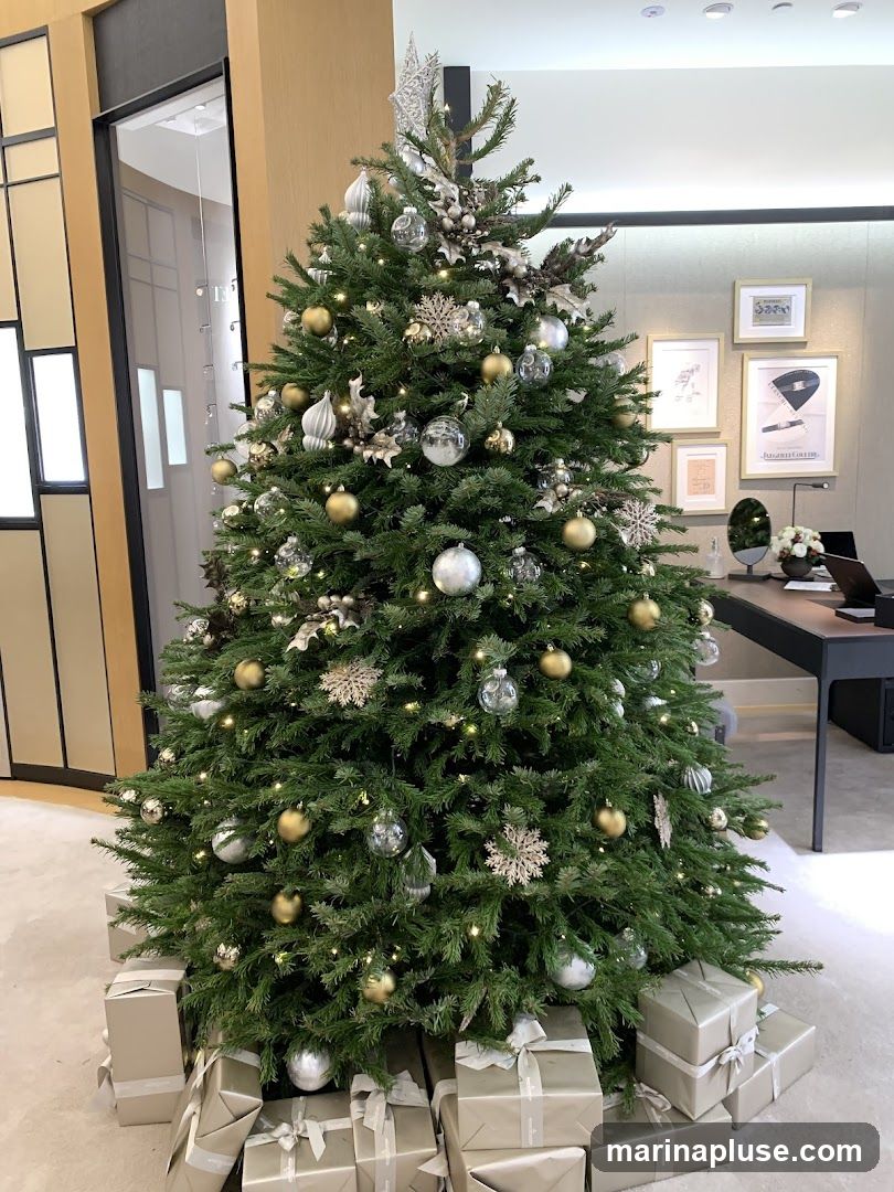 A decorated Christmas tree with gold and silver ornaments and lights, surrounded by wrapped gifts. In the background, there is a desk with a laptop and some framed pictures on the wall.