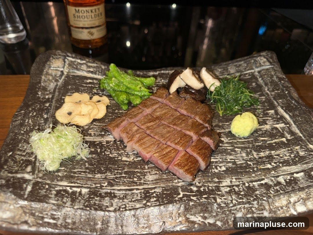 A plate of sliced steak is served with various accompaniments, including green beans, mushrooms, shredded green onions, crispy chips, and a dollop of green paste. A bottle of Monkey Shoulder whiskey is visible in the background.
