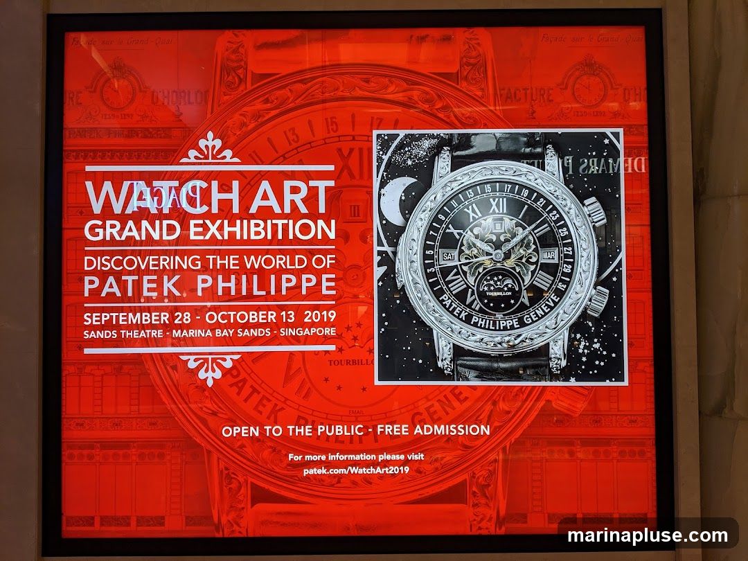 A digital advertisement for the Patek Philippe Watch Art Grand Exhibition, featuring a large image of a Patek Philippe watch with a moon phase complication. The text announces the exhibition dates as September 28 - October 13, 2019, held at the Sands Theatre, Marina Bay Sands, Singapore. Admission is free and open to the public. A website for more information is provided.