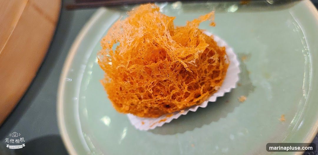 A close-up shot of a golden-brown fried taro ball on a light green plate. The taro ball has a crispy, intricate, web-like exterior.