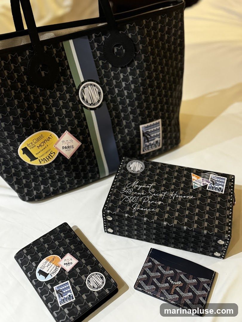 A collection of luxury accessories including a tote bag, a clutch, a passport holder, and a cardholder, all featuring intricate patterns and branding. The items are arranged on a white surface.