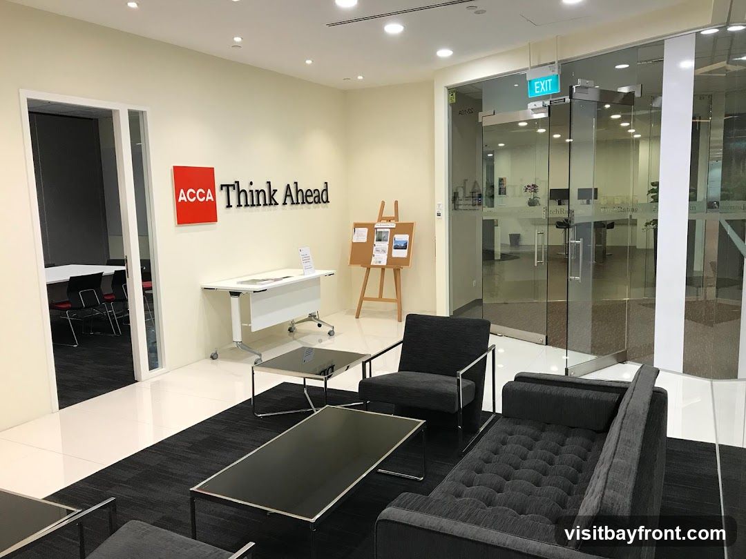 A modern office reception area with seating, a conference room visible through a glass door, and the ACCA Think Ahead branding on the wall.