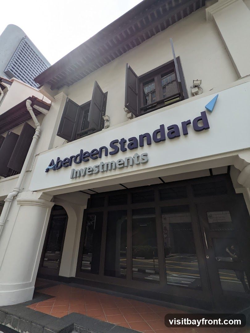The exterior of a building with the sign "Aberdeen Standard Investments" above a glass-fronted entrance. The building has traditional shutters on the upper windows.
