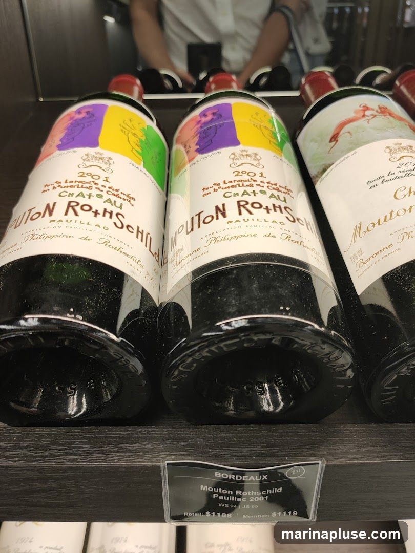 Several bottles of Mouton Rothschild Pauillac 2001 wine are displayed on a shelf. A price tag indicates the retail price is $1188 and the member price is $1119.