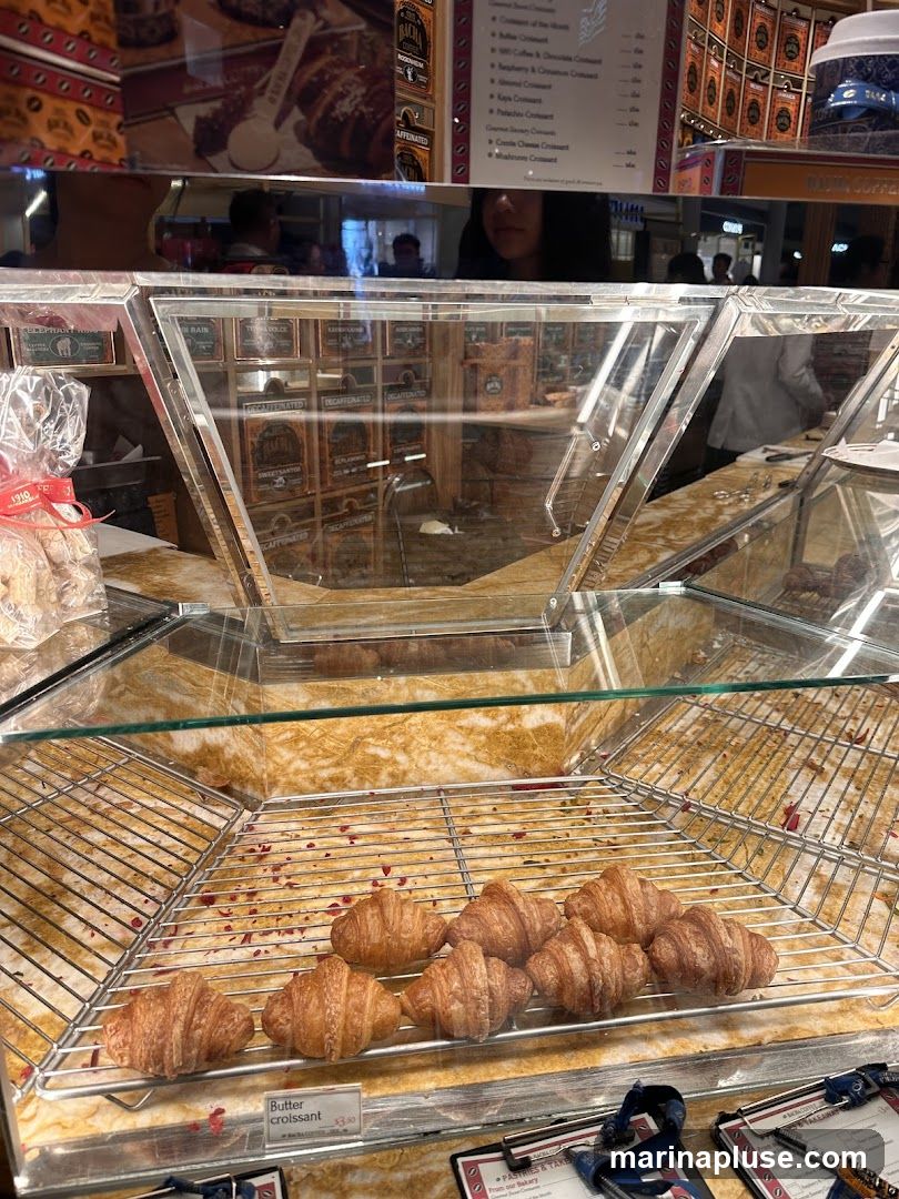 A display case with several croissants and a menu board listing various croissant options.