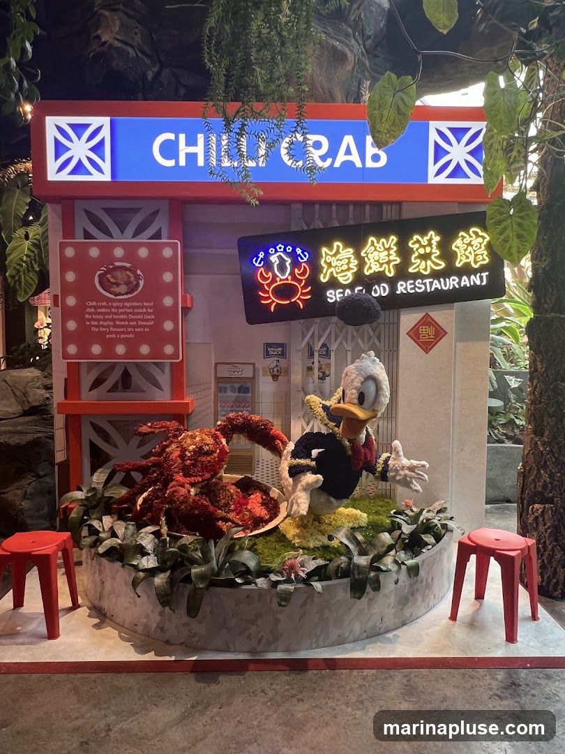 A decorative display featuring a large chili crab sculpture and a Donald Duck figurine, set against a backdrop with signage for "CHILLI CRAB" and "SEAFOOD RESTAURANT". Two red stools are placed on either side of the display.