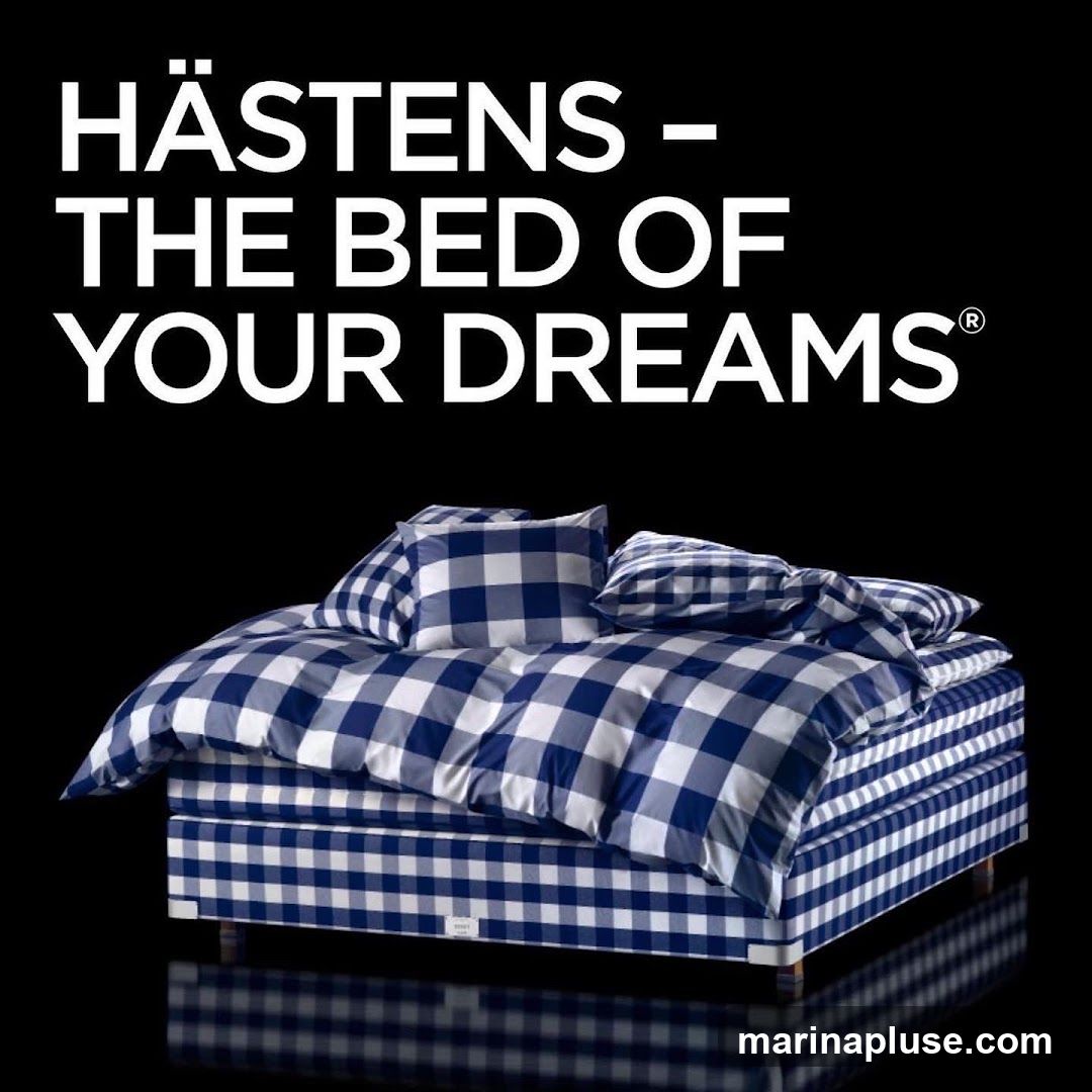 A Hästens bed with blue and white checkered bedding is displayed against a black background. White text above the bed reads "HÄSTENS - THE BED OF YOUR DREAMS®".