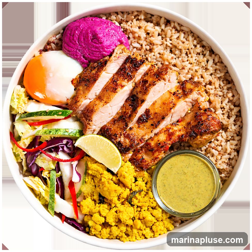 A top-down view of a healthy bowl with brown rice, sliced grilled chicken, a soft-boiled egg with a bright orange yolk, a dollop of vibrant purple hummus, a side of scrambled tofu, a fresh salad with cabbage, cucumber, and red pepper, a lime wedge, and a small bowl of green dressing.