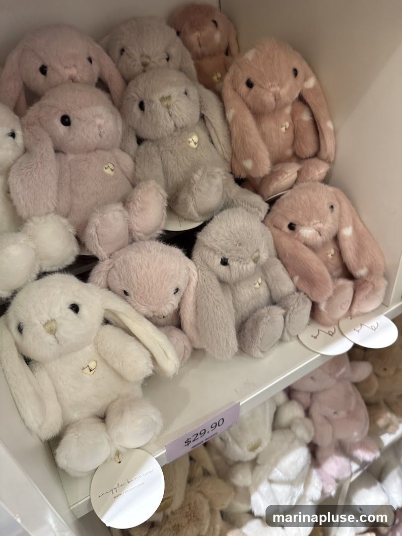 A shelf filled with various plush bunnies in pastel colors like pink, grey, and cream. Some bunnies have white polka dots. A price tag of $29.90 is visible.