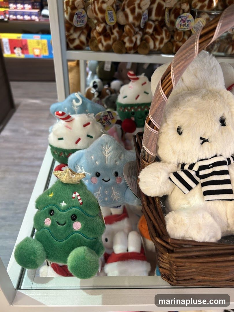 A display of various plush toys, including Christmas-themed cupcakes, a snowflake, a Christmas tree, and a white bunny in a basket. In the background, giraffe plush toys are visible on a shelf.