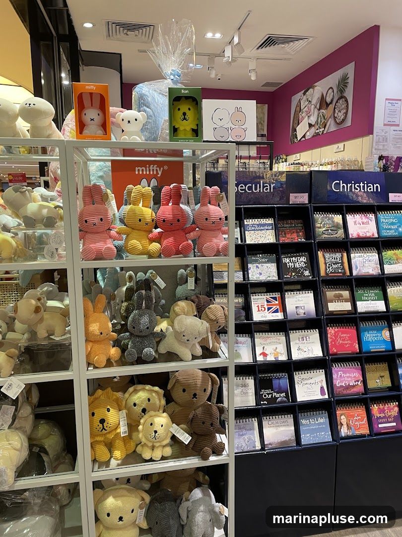 A retail display featuring a variety of plush toys, including Miffy characters, bunnies, lions, and dogs, arranged on shelves. To the right, a display of calendars is organized under 'Secular' and 'Christian' sections, with titles like '165 Days of Love', 'Our Planet', and 'Promises from God's Word'.