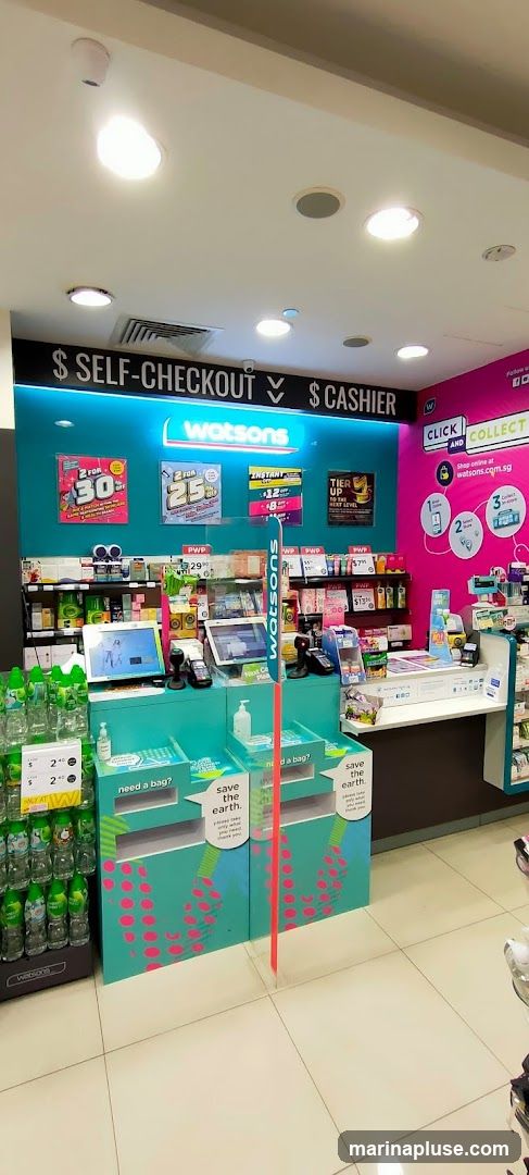 The image shows the checkout area of a Watsons store. There are self-checkout stations and a cashier counter. Promotional signs for discounts are displayed on the wall. Recycling bins are placed in front of the checkout counters. Shelves stocked with various products are visible in the background.