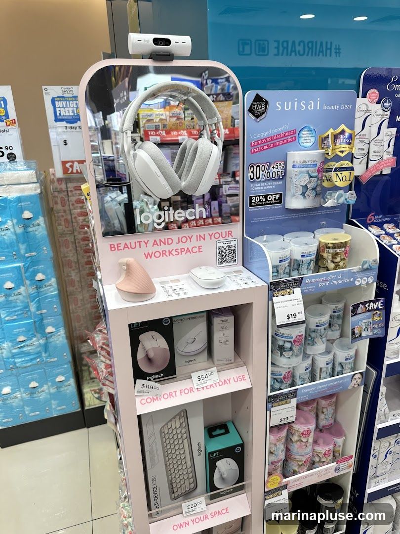 A retail display featuring Logitech computer accessories and beauty products. The Logitech section showcases headphones, mice, and keyboards with prices. The beauty section displays various skincare items, including a promotion for Suisai beauty clear products.