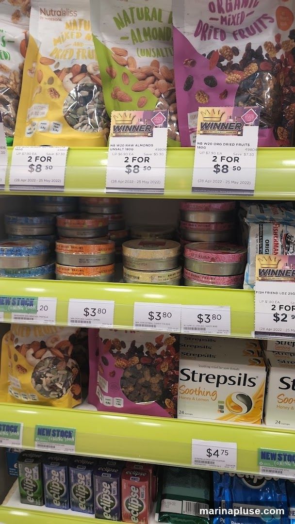 Shelves stocked with various snacks, including bags of mixed nuts and dried fruits, tins of candy, boxes of Strepsils lozenges, and packs of Eclipse mints. Promotional labels indicate sales and new stock.