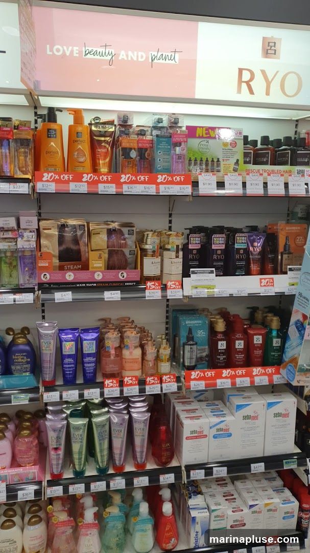 A retail display shelf filled with various beauty and personal care products, including shampoos, conditioners, hair treatments, and skincare items. Prominent brands visible include Love Beauty and Planet, RYO, Perfect, L'Oréal, and Sebamed. Many items are marked with "20% OFF" or "15% OFF" sale signs.