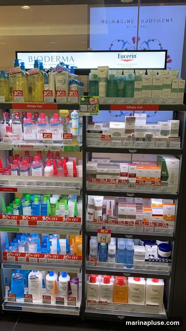A retail display featuring skincare products from Bioderma and Eucerin. The shelves are organized with various cleansers, moisturizers, and treatment creams. Promotional signs indicating discounts like "20% OFF" and "30% OFF" are visible. The display includes brand logos and product names.