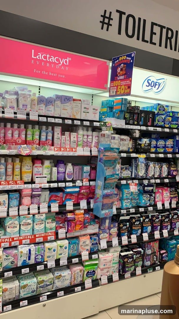 A retail display shelf stocked with various feminine hygiene products, including sanitary pads and panty liners. Brands visible include Lactacyd, Eve, Kotex, Carefree, and Sofy. Promotional signs indicate discounts such as "BUY 2 GET 1 FREE" and "SAVE UP TO 50% OFF".