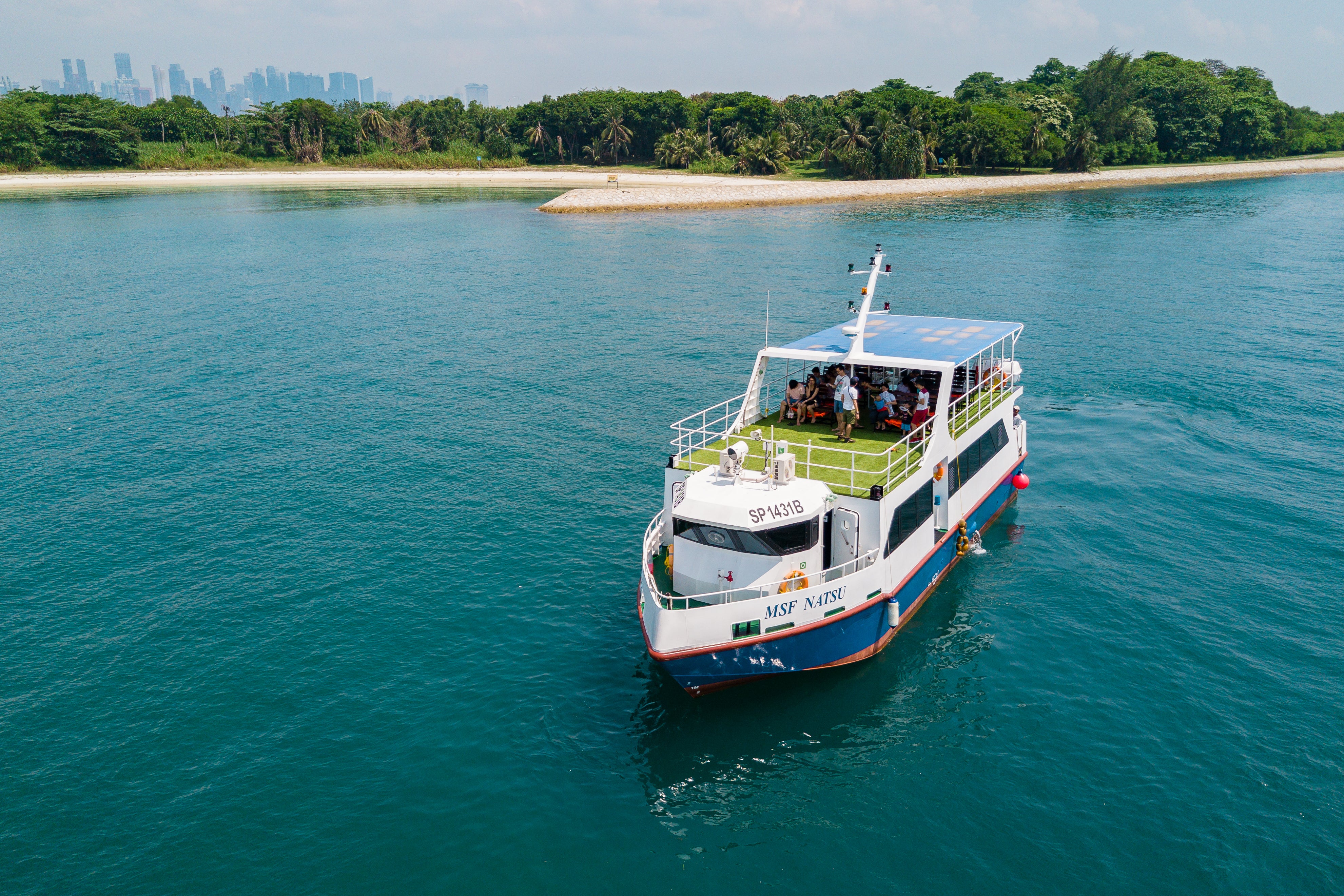 Aerial view of a Marina South Ferries vessel at Marina South Pier with the Singapore skyline behind